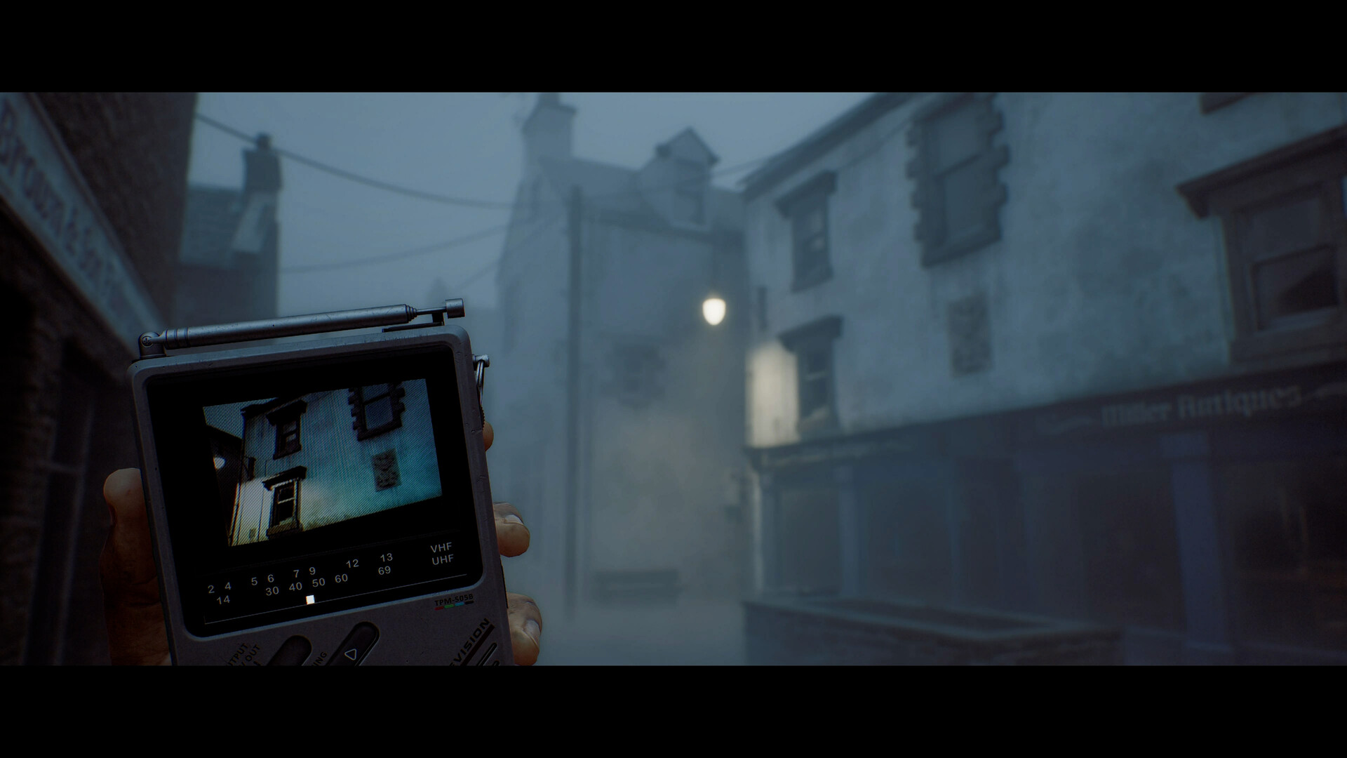 Official SILENT HILL: Townfall Steam still — first-person view holding the CRTV pocket television on a fog-soaked St. Amelia street