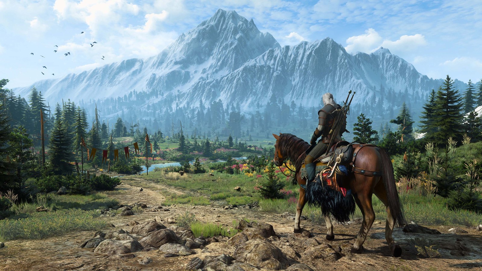 Official The Witcher 3 Remastered still — Geralt on Roach overlooking a sunlit valley toward a snow-capped mountain peak